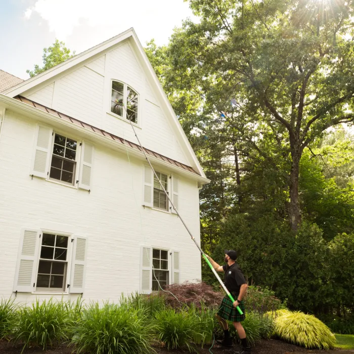 a person standing in front of a house cleaning the windows