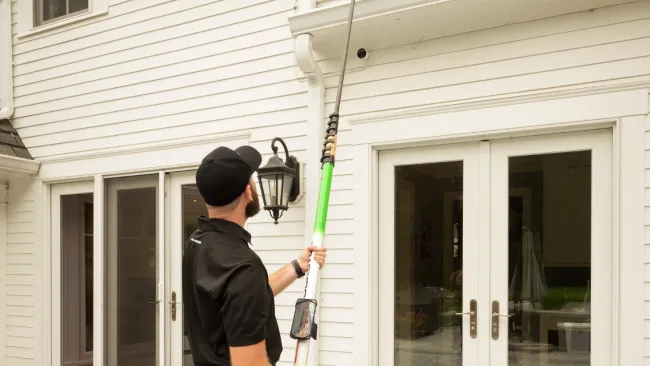 a person holding a pole with a gutter camera