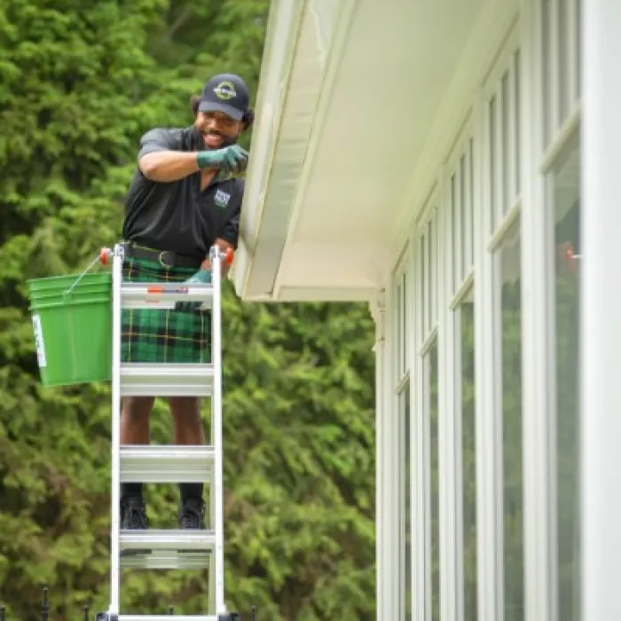 a person on a ladder cleaning gutters