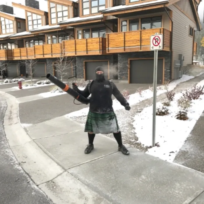 a person in a kilt holding a leaf blower on a street corner