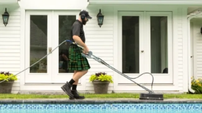 a man wearing a kilt and cleaning concrete