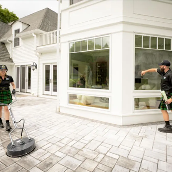 A man and woman cleaning the exterior of a home