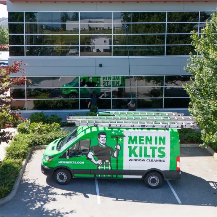 Men In Kilts branded van parked near a building with a worker cleaning windows.